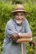 senior posing with a spade in the garden