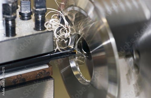 Fine turnings fly off a fast spinning metal lathe