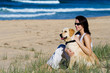 Foto: Young female sitting on a beach with a dog Young female sitting on a beach with a dog