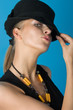 Young fashion model posing in hat against blue background Young fashion model posing in hat against blue background