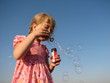 little girl blowing away soap bubble