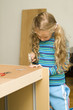 Girl helping to assemble a new furniture Girl helping to assemble a new furniture