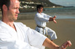 Young adult men with black belt practicing a Kata on the beach
