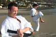 Young adult men with black belt practicing a Kata on the beach 
