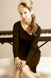 Latina female in elegant dress sitting by piano keyboard