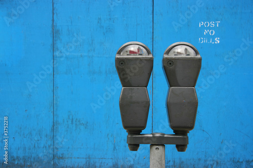 Two parkmeters over blue wooden panels Two parkmeters over blue wooden panels