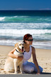 Foto: Young female sitting on a beach with a dog Young female sitting on a beach with a dog
