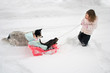 a big sister pulling her little sister in a sled