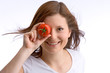 junges, schönes Mädchen hält eine Tomate zu ihrem Auge