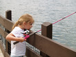 young girl looking bored while fishing from the dock