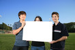 Photo: Three young friends holding a blank white billboard Three young friends holding a blank white billboard
