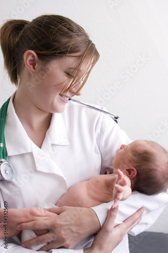 Photo: A young female doctor smiling at a newborn baby. A young female doctor smiling at a newborn baby.