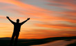 Man with outstretched arms facing a beautiful sunset.