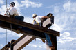 Two ironworkers atop the skeleton of a modern building Two ironworkers atop the skeleton of a modern building