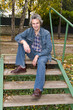 Smiling middleaged man in a jean suit sitting on the stairs