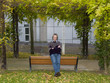 Middleaged man in a sweater and jeans sitting on a bench
