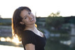 Smiling latin brunette girl in a black blouse in a backlight