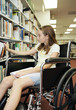 girl in a wheelchair selecting a book at the library.