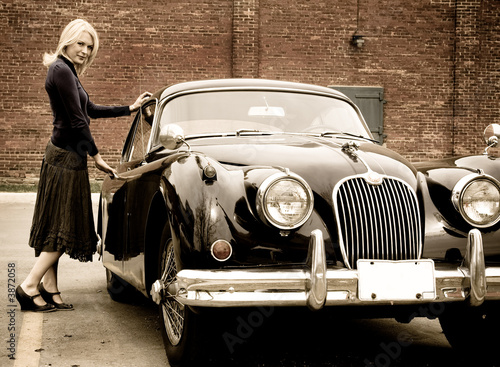A beautiful blond woman getting into a classic car
