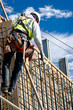 A construction worker on a high wall against a cloudy sky.
