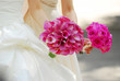 Bride and bridesmaid holding bouquets of pink flowers