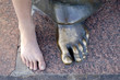 Foots of the teenager and bronze sculpture.