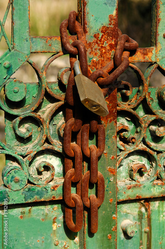 Photo: Rusty chain and padlock lock on an heavily weathered door Rusty chain and padlock lock on an heavily weathered door