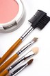 Cosmetic brushes with face powder in white background.
