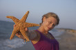 cute girl is holding up an seastar