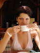 Wide-open girl drinking coffee with pleasure and scarcely smile