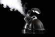 Tea kettle with boiling water on black background