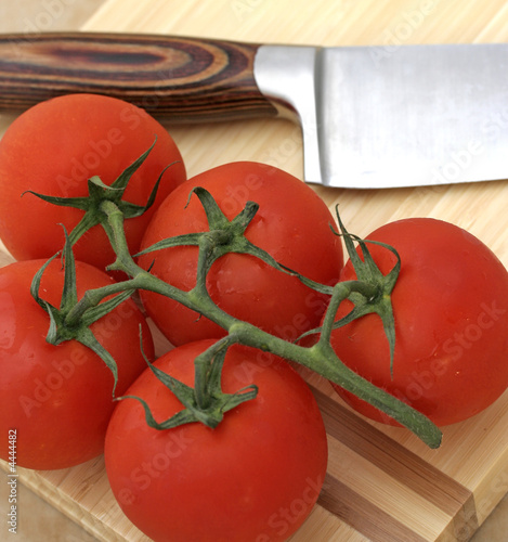 Tomatoes on chopping board with knife