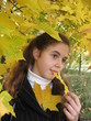 The young girl with yellow leaves in an autumn