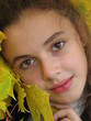 The portrait of young girl with yellow leaves in an autum