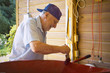 Senior painting a wheel barrow in red -  expressive face