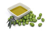 Oilve oil in a square bowl, with some green olives around