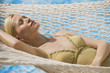 Woman relaxing in a hammock with water behind