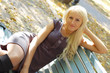 Blond girl sits on a bench in autumn park