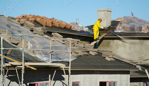 Construction worker washes exterior walls new home.