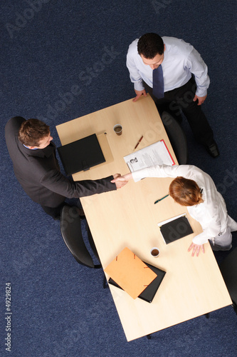Photo: business man and woman formal handshake over table business man and woman formal handshake over table