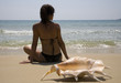 Young girl sitting on the sand with shell  