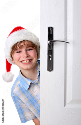 Foto: Boy with Santa's Hat peeking behind the door Boy with Santa's Hat peeking behind the door