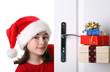 Girl with Santa's Hat peeking behind the door