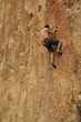 Bare back climber clinging to rock face