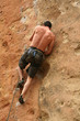 Bare back climber clinging to rock face