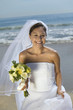 Bride with bouquet on beach, smiling, portrait