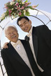Groom with father under archway, outdoors, portrait