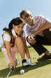 Golfer helping teenage girl line up shot