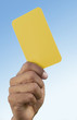 Soccer referee holding up yellow card, close-up on hand