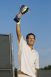 Tennis Player Proudly Holding Trophy in Air